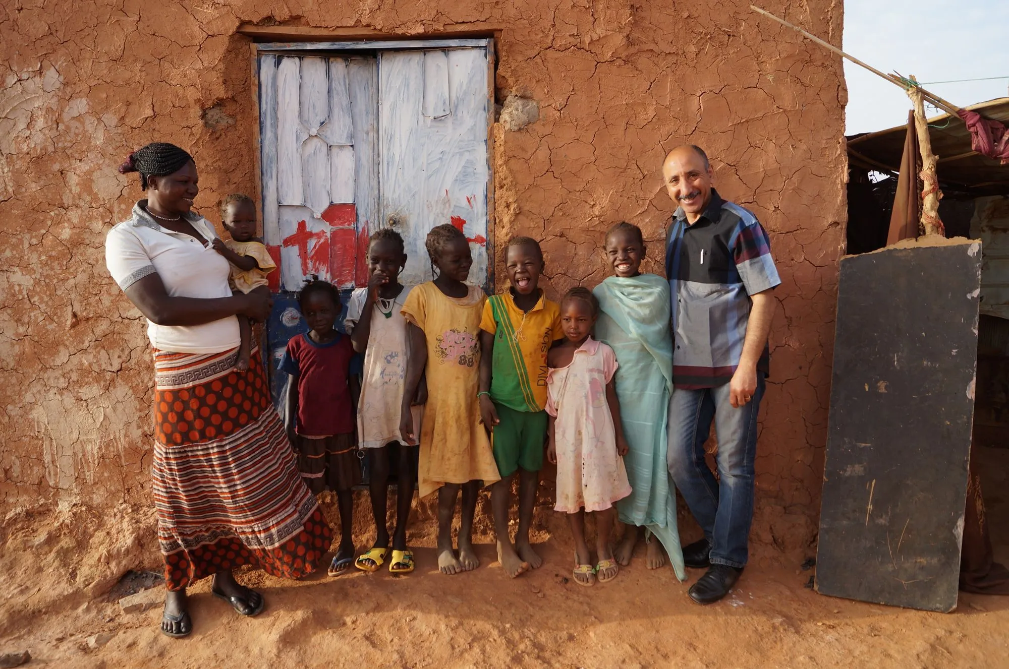 Eine Familie mit mehreren Kindern steht vor ihrem Lehmhaus in einem Slum.